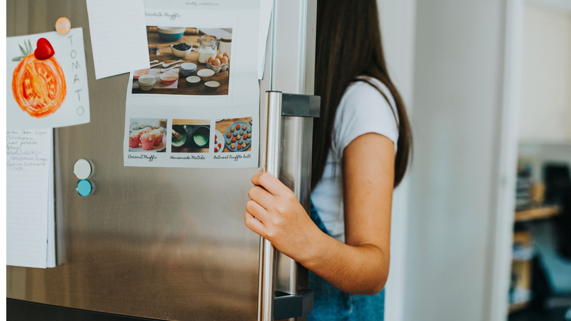 pessoa abrindo a porta de uma geladeira em cozinha doméstica, representando o consumo de energia do eletrodoméstico