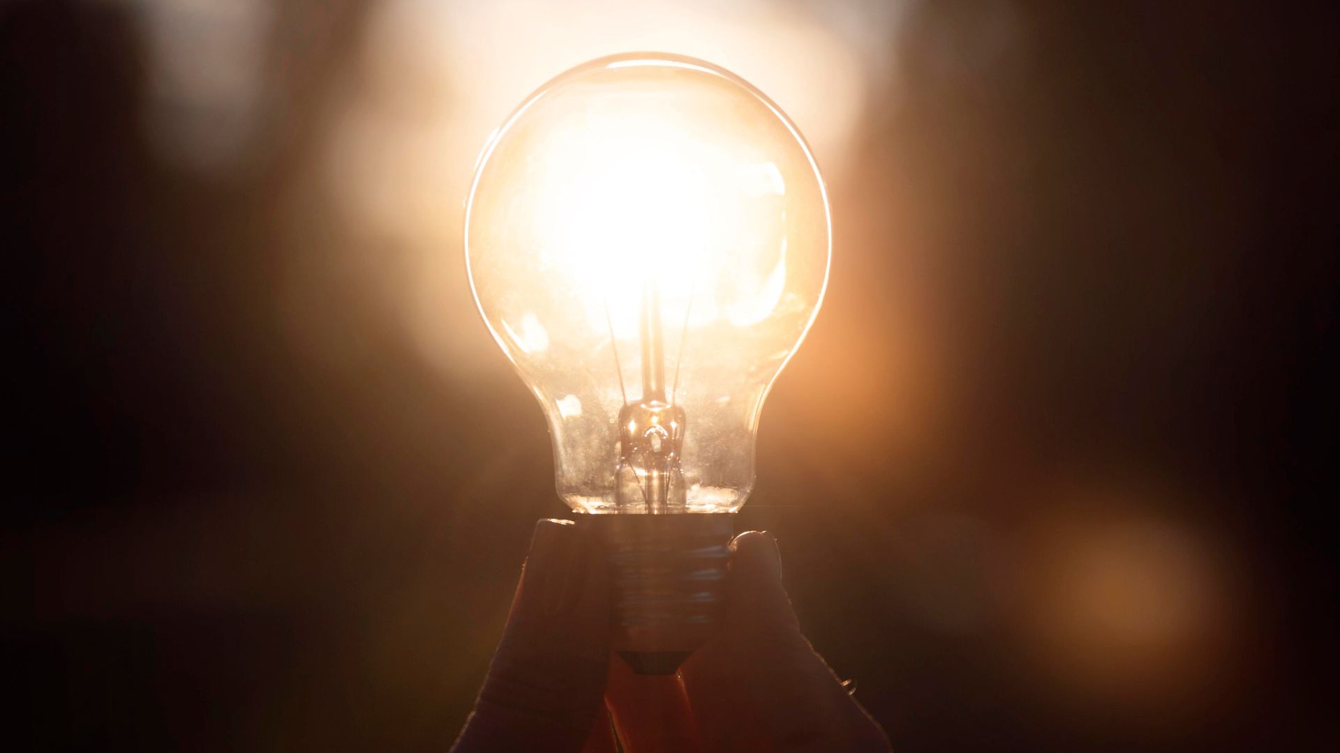 Lâmpada acesa sendo iluminada pela luz do sol, simbolizando a transição energética e o crescimento das fontes renováveis no Brasil.