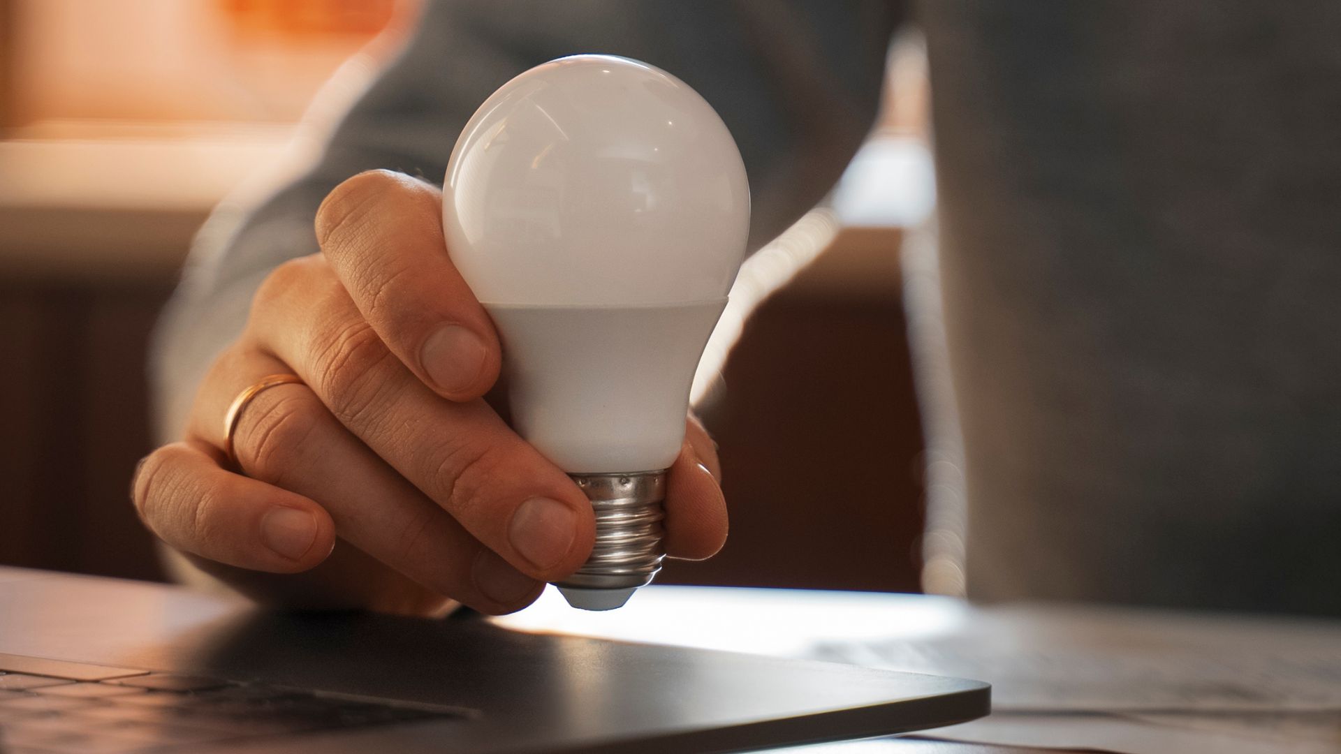 Pessoa segurando uma lâmpada LED, simbolizando escolhas para reduzir o consumo e diminuir a conta de luz.