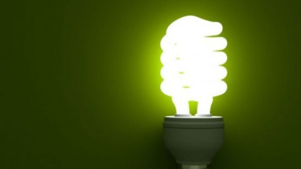 Lâmpada fluorescente acesa com luz verde, representando economia de energia e bandeira tarifária verde na conta de luz.